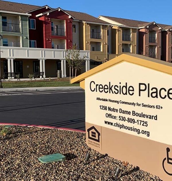 An image of Creekside Place Apartments on a sunny morning shows the front east wing behind a large monument-style sign that reads "Creekside Place."